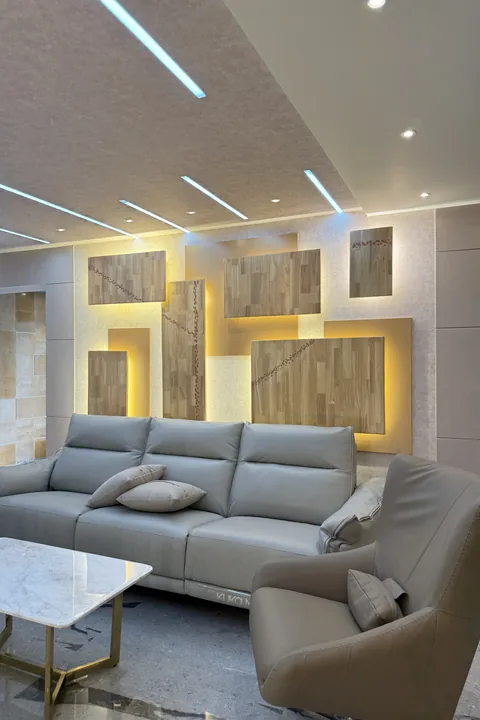 Living room with an L-shaped sofa and backlit timber wall panelling, by Kalky Interior