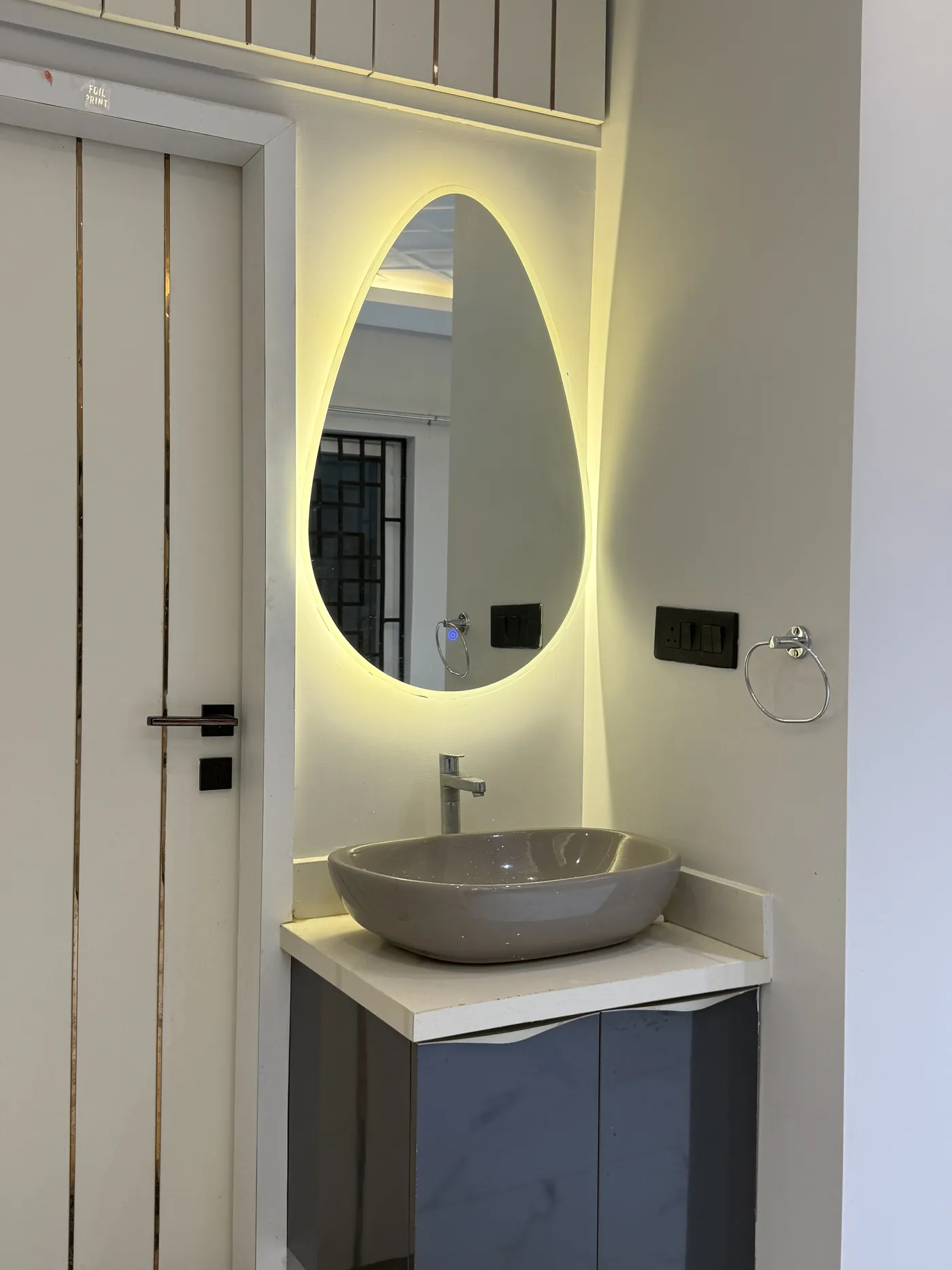 Bathroom vanity with a vessel basin and an oval backlit mirror