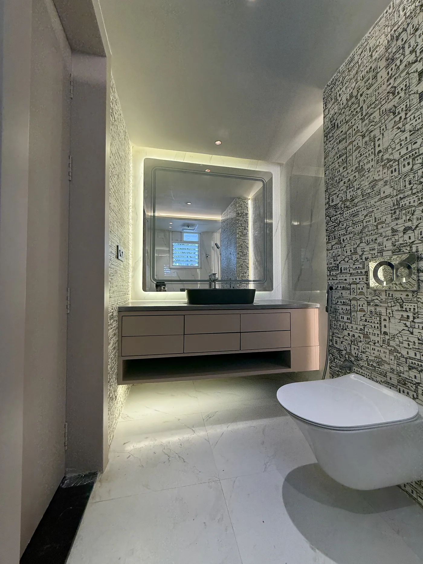 Bathroom with a floating vanity, backlit mirror and a stone wall