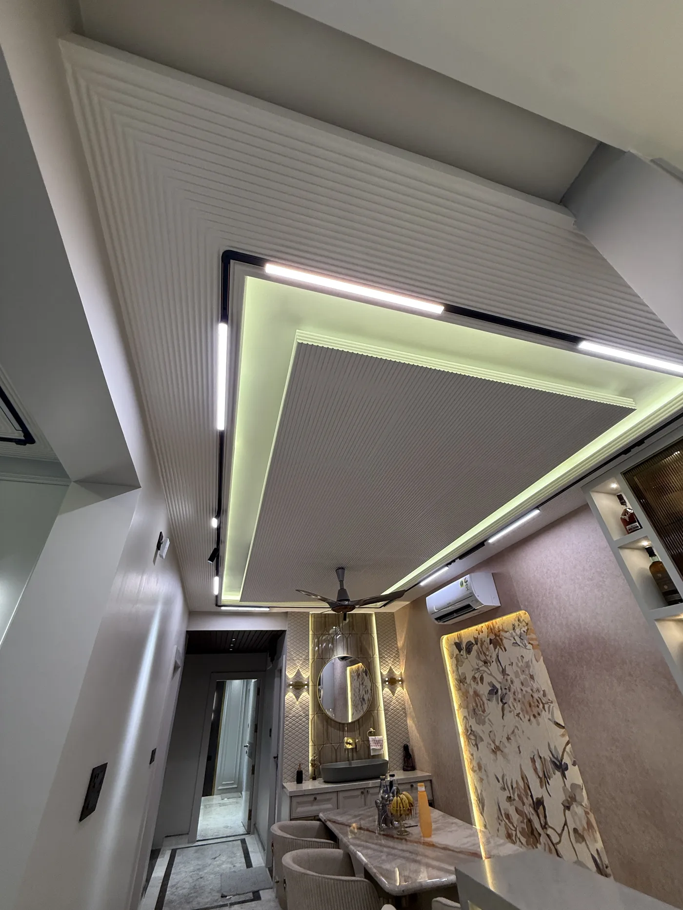 Layered false ceiling with concealed cove lighting over a passage