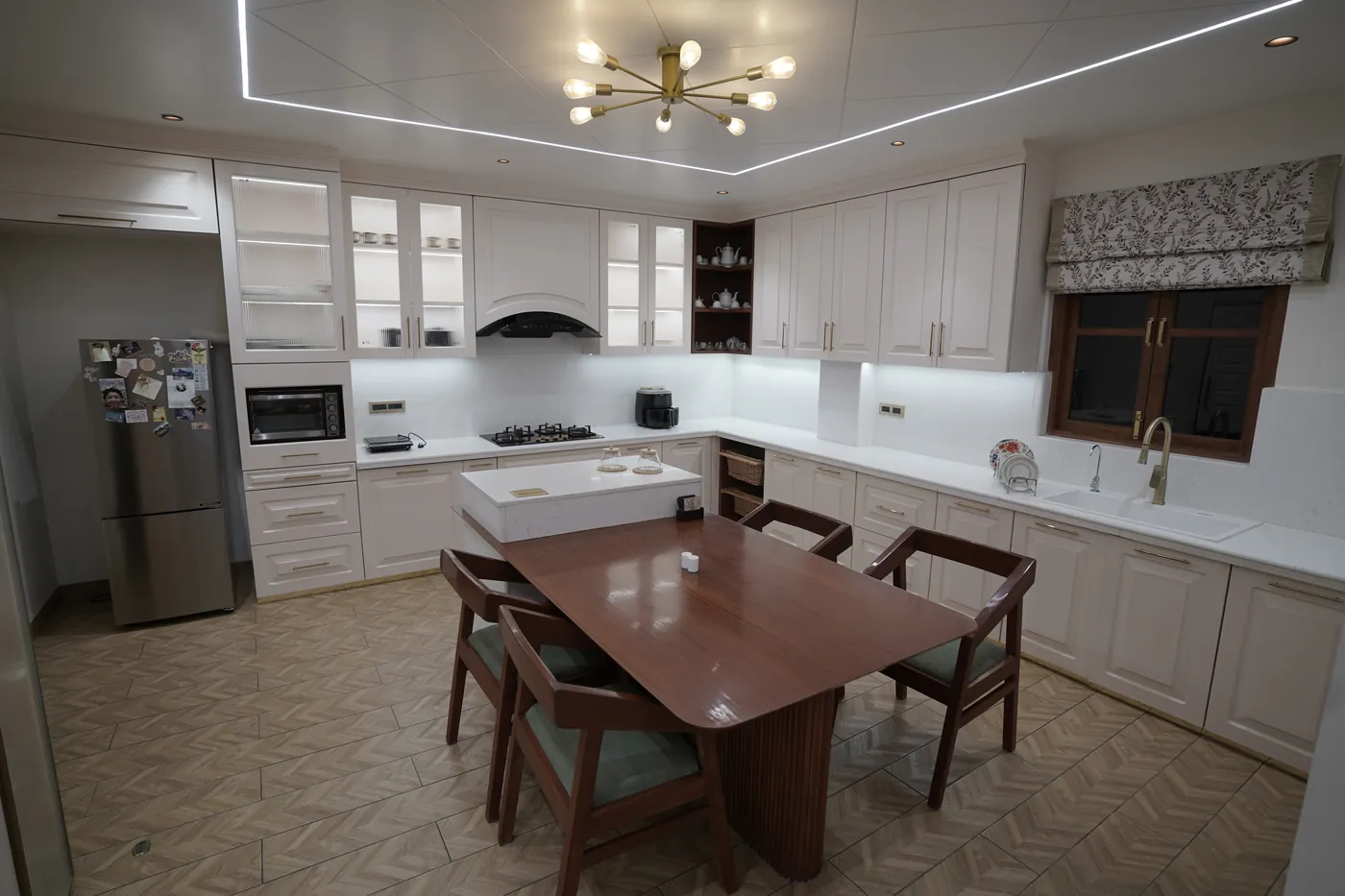 Open kitchen and dining room with a timber table and a brass sputnik chandelier