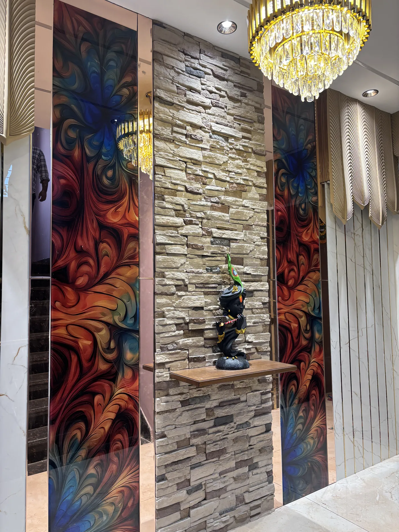Foyer with stone cladding, a decorative resin panel and a crystal chandelier