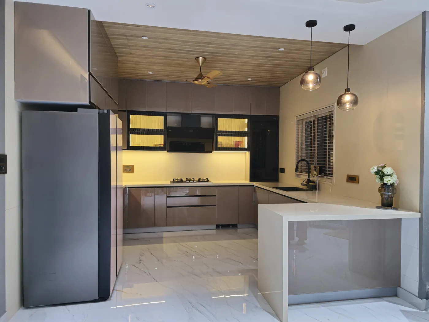 Grey and mocha modular kitchen with glass pendant lights over a peninsula