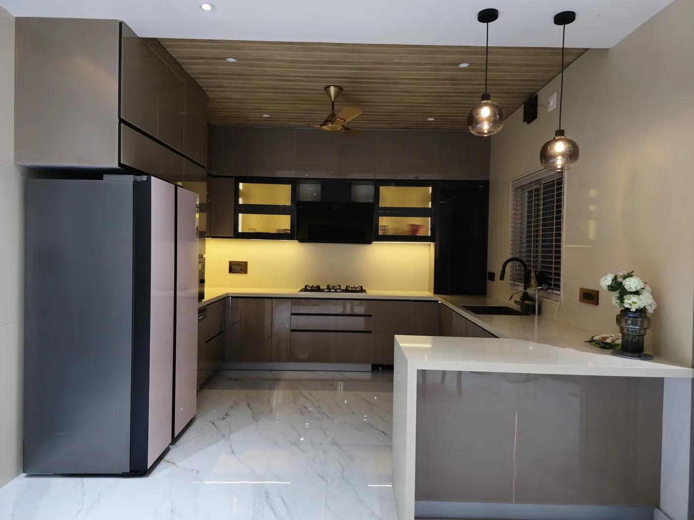 U-shaped modular kitchen in mocha laminate with under-cabinet lighting