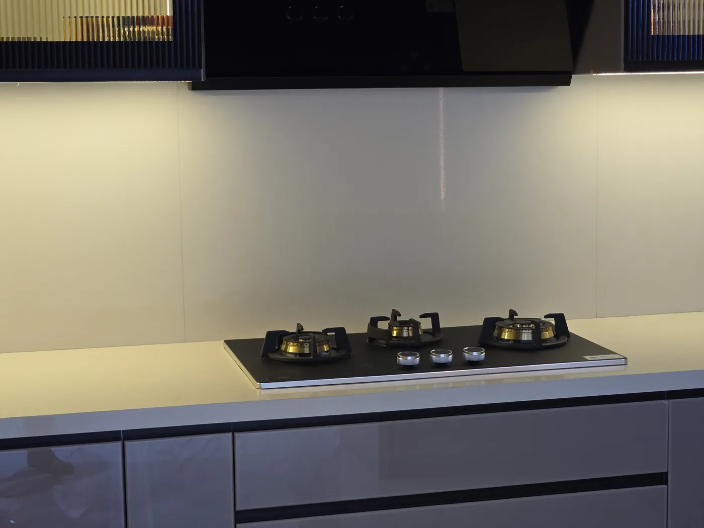 Gas hob set into a dark quartz worktop with a wall-mounted chimney