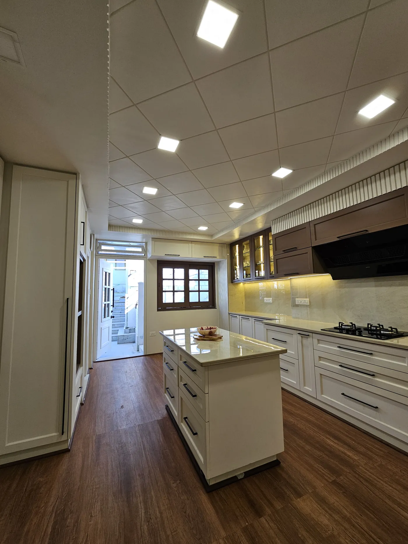 Galley kitchen in white with a central island and oak flooring