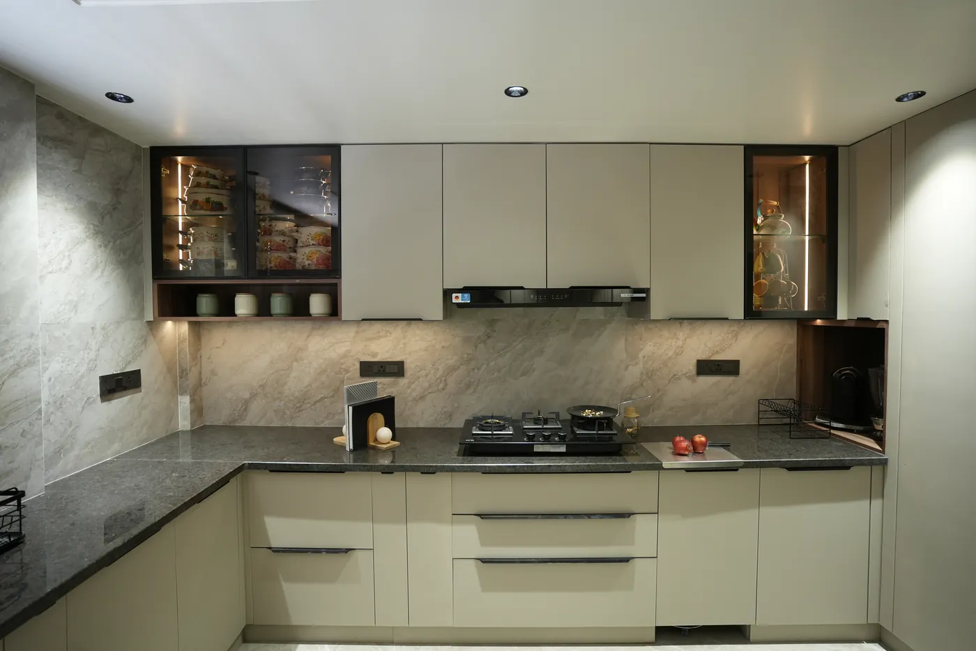 Cream modular kitchen with a dark stone worktop and a built-in hob