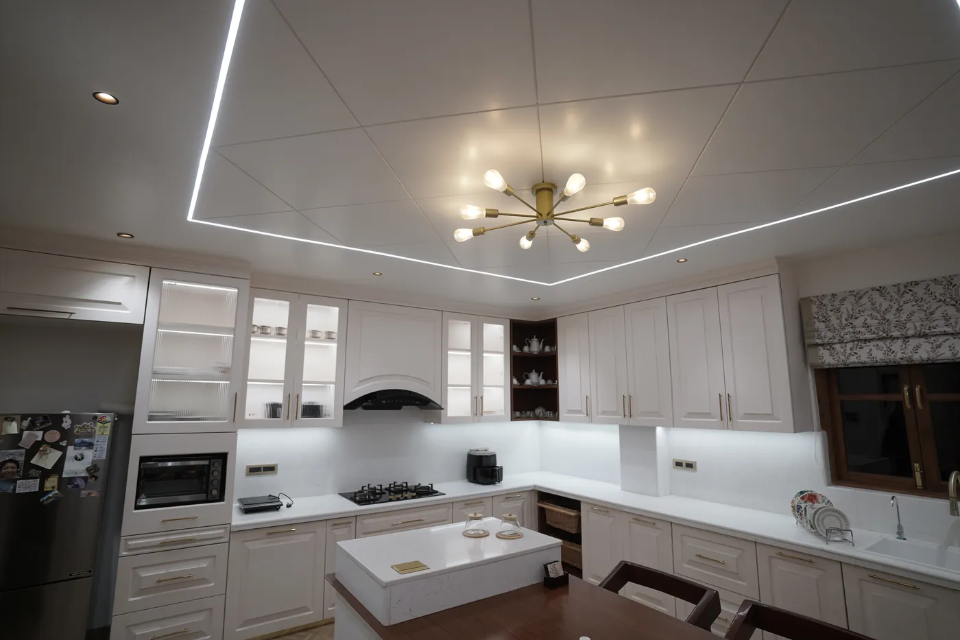 White kitchen with a marble island and a brass sputnik chandelier