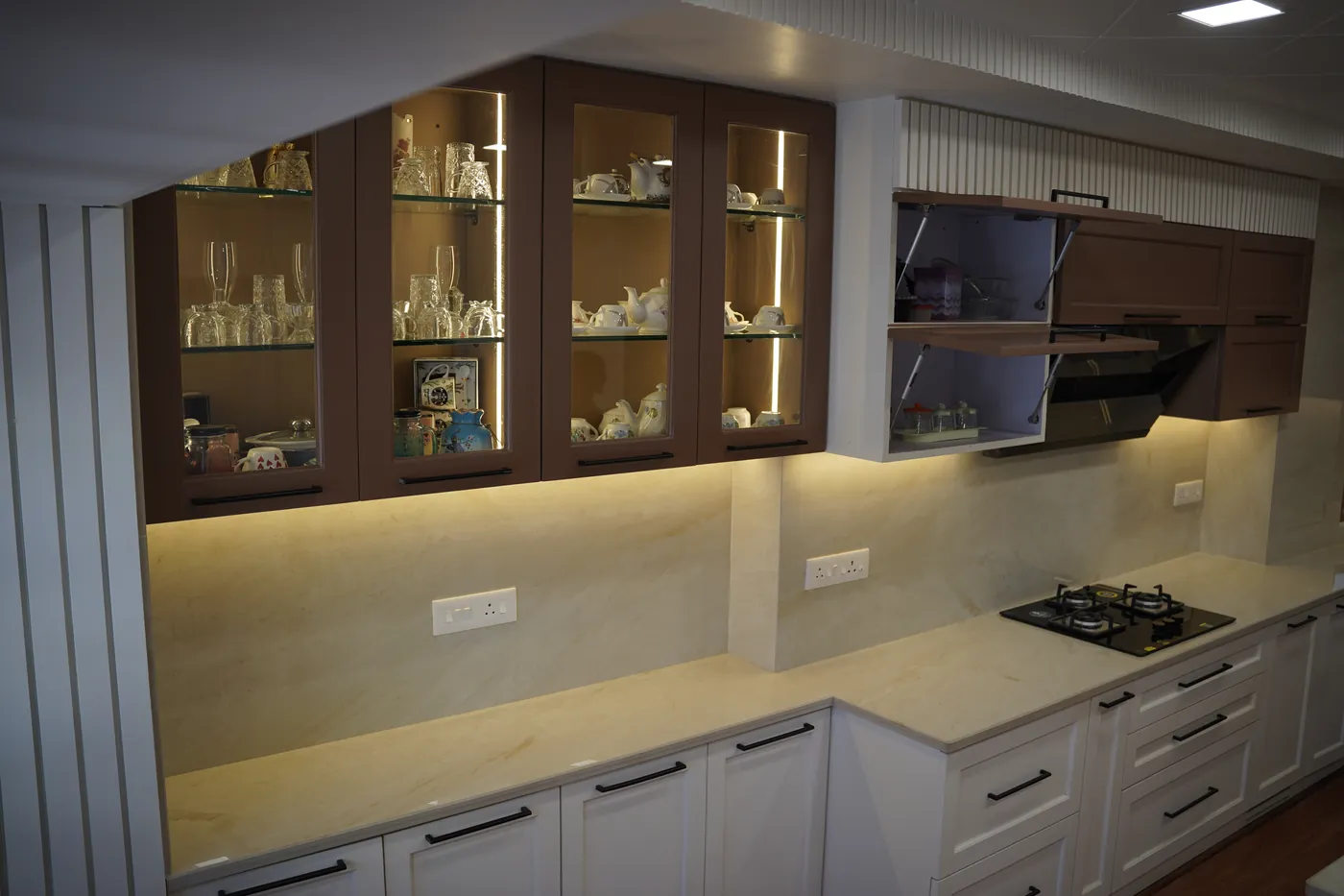 Backlit glass display cabinets above a kitchen worktop with a hob
