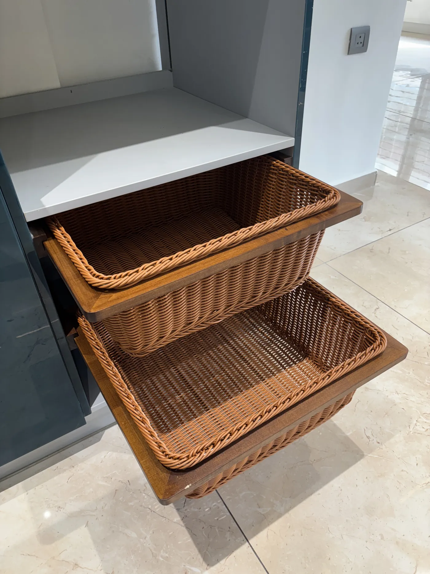 Wicker pull-out basket drawers inside a kitchen tall unit