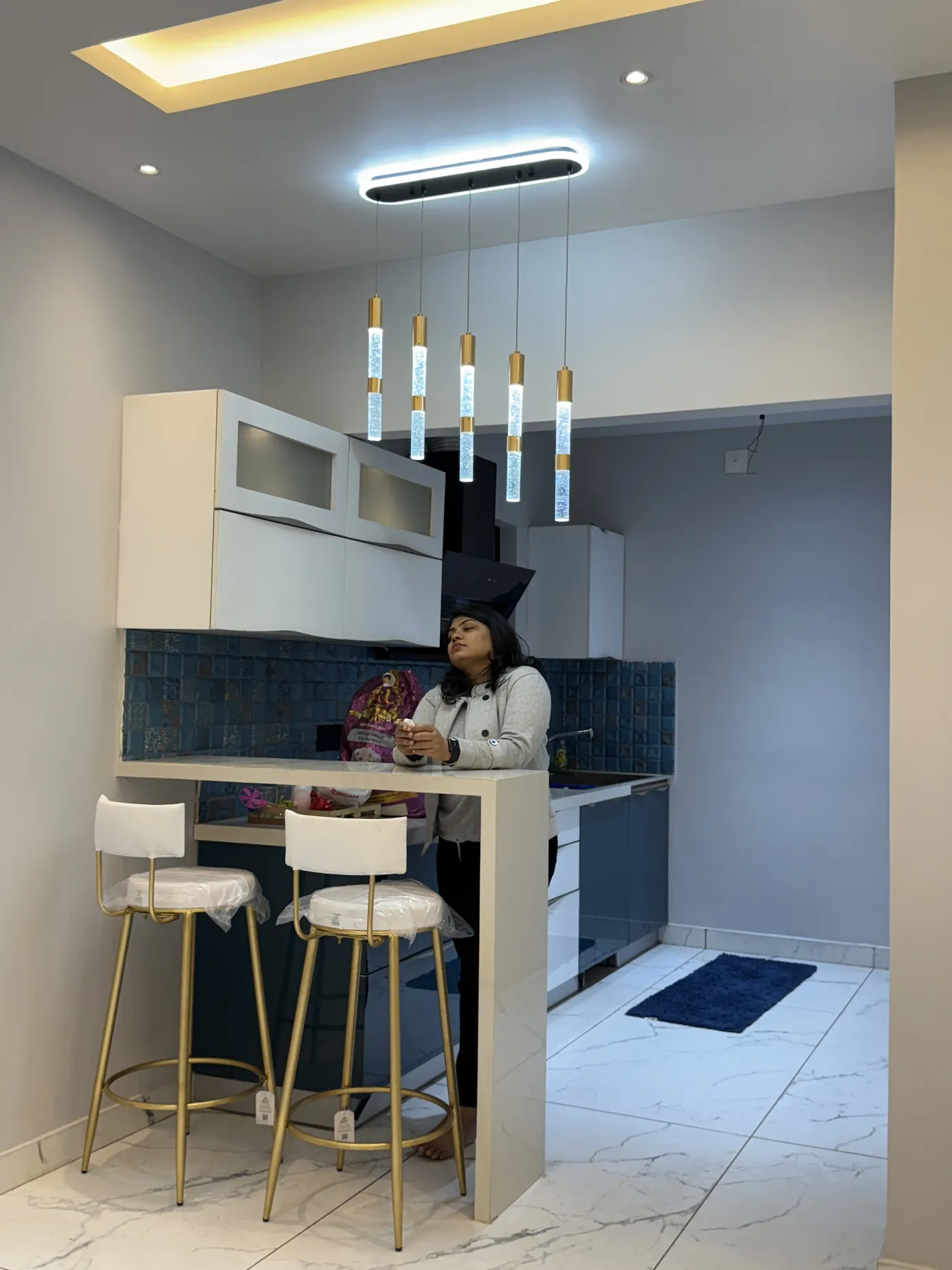 Breakfast bar with upholstered stools and a teal tiled kitchen behind