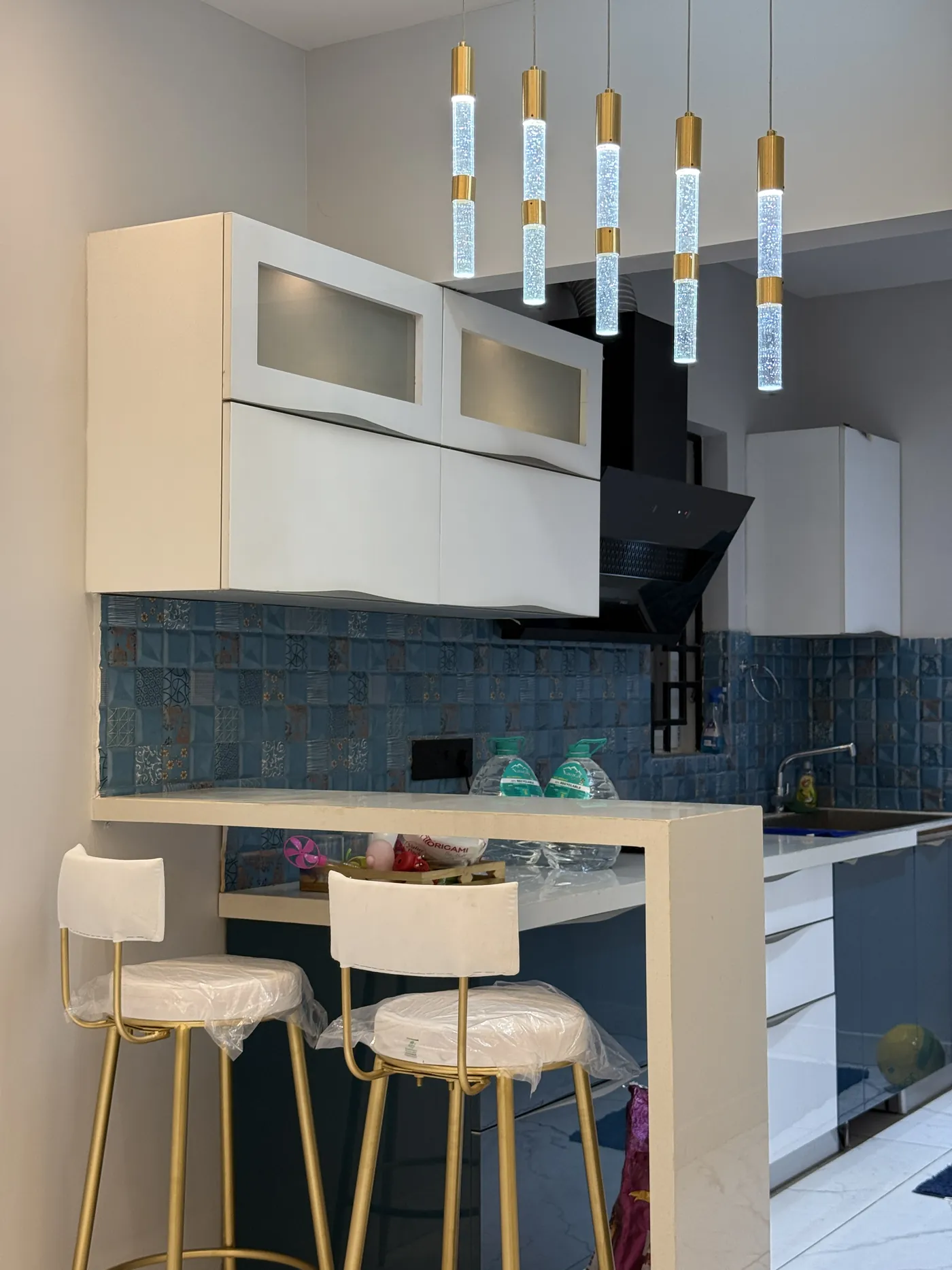 Kitchen breakfast bar with pendant lights and a teal tiled splashback