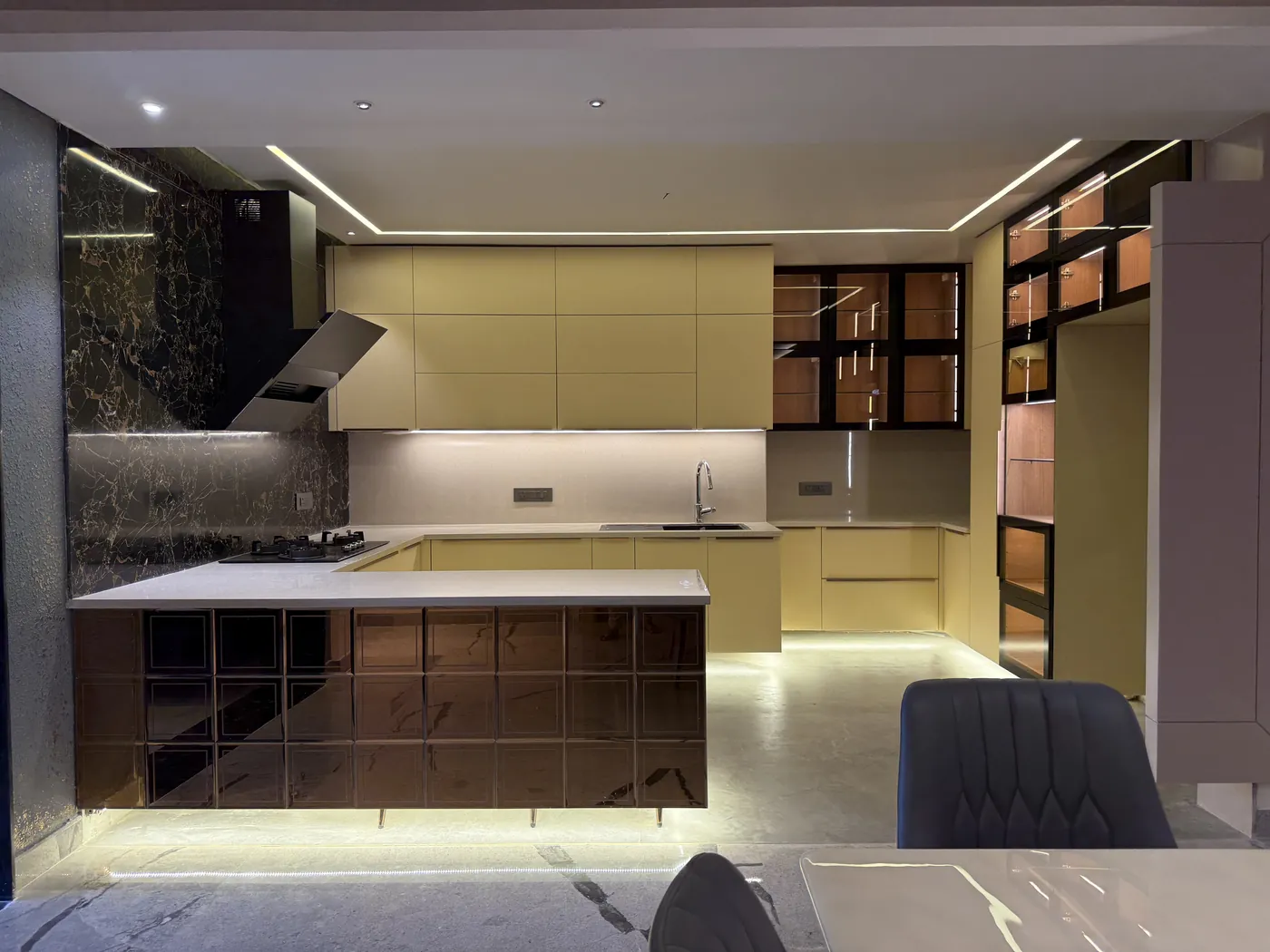 Kitchen with cream cabinets, a dark marble island and a wall chimney