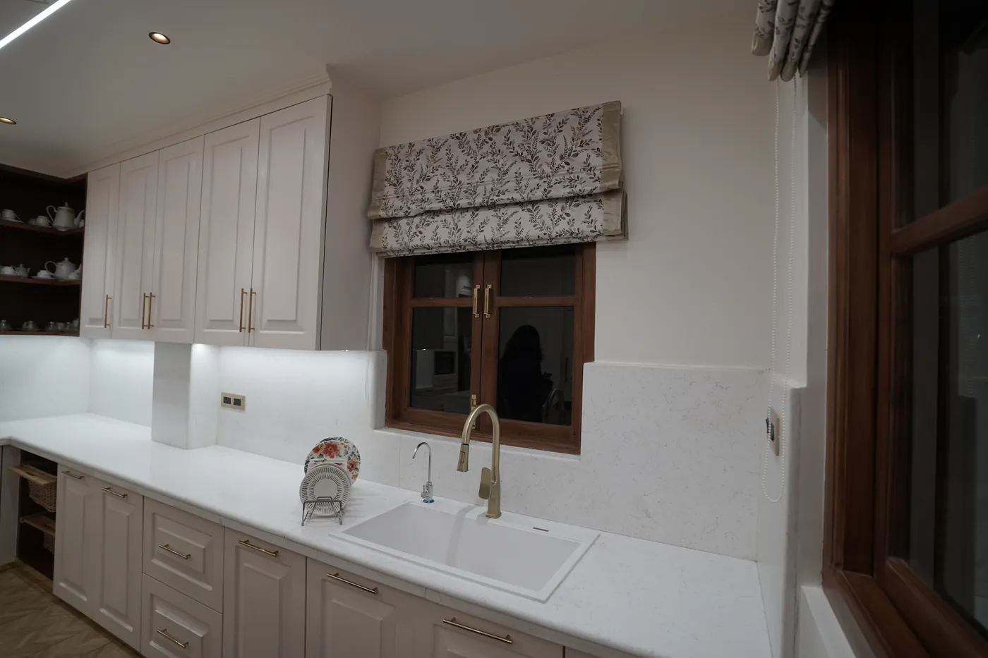 Kitchen sink set under a window with shaker cabinets in white
