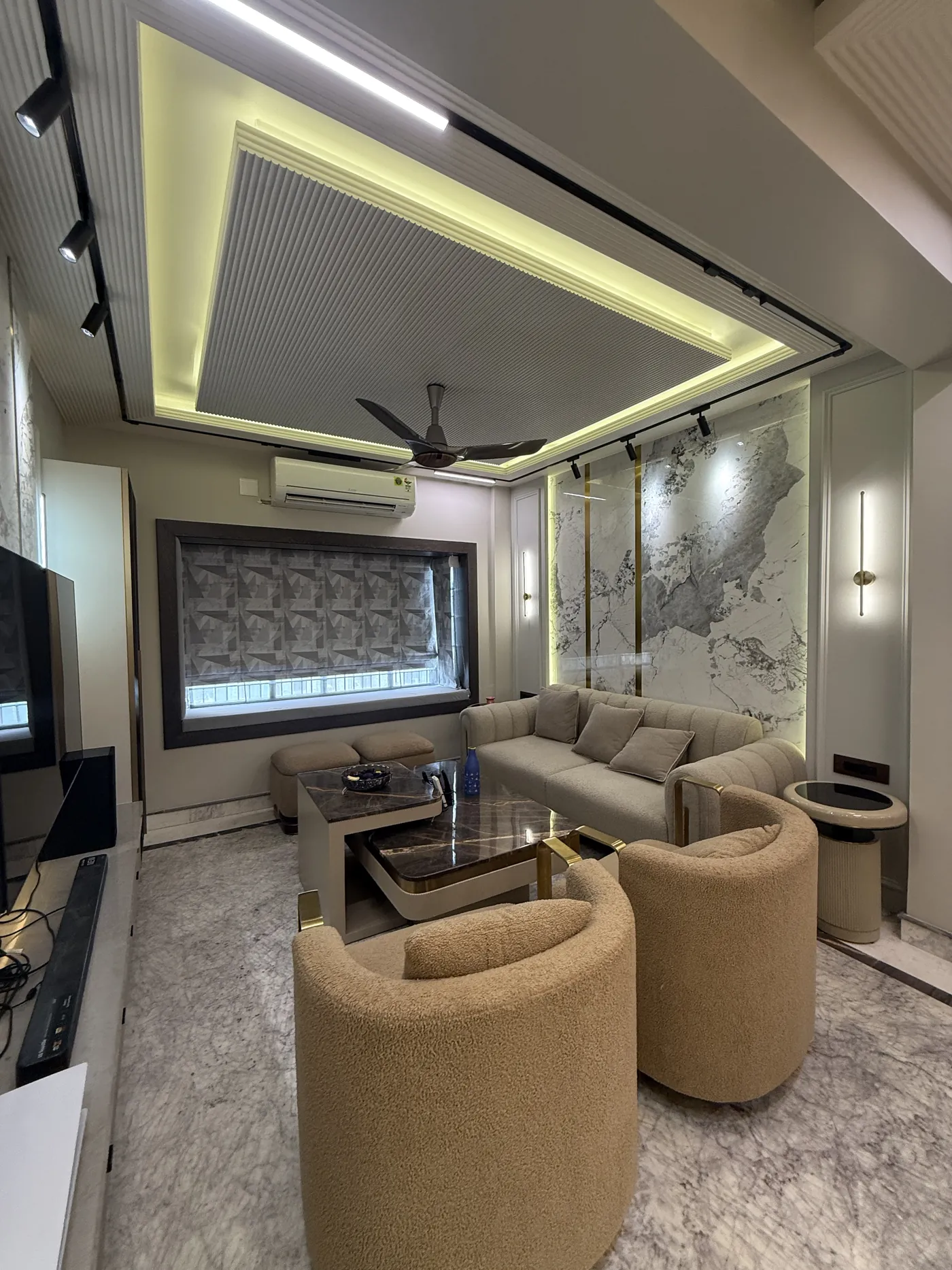 Living room with a timber TV unit and a layered false ceiling, built by Kalky Interior in Bhubaneswar