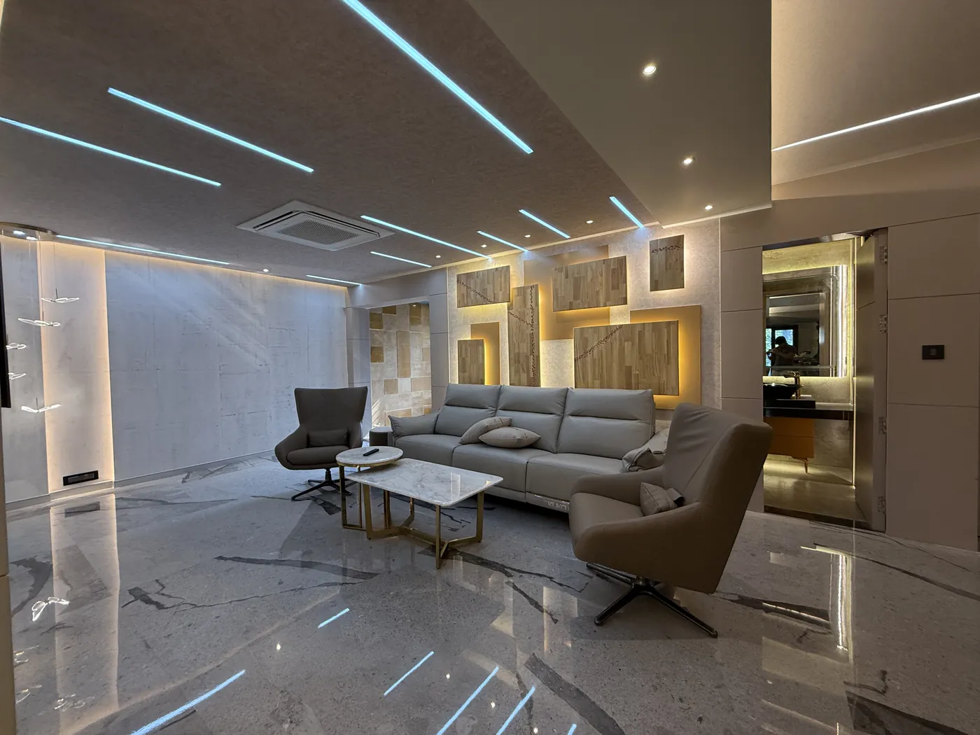 Living room with a grey sofa, swivel chairs and a marble floor