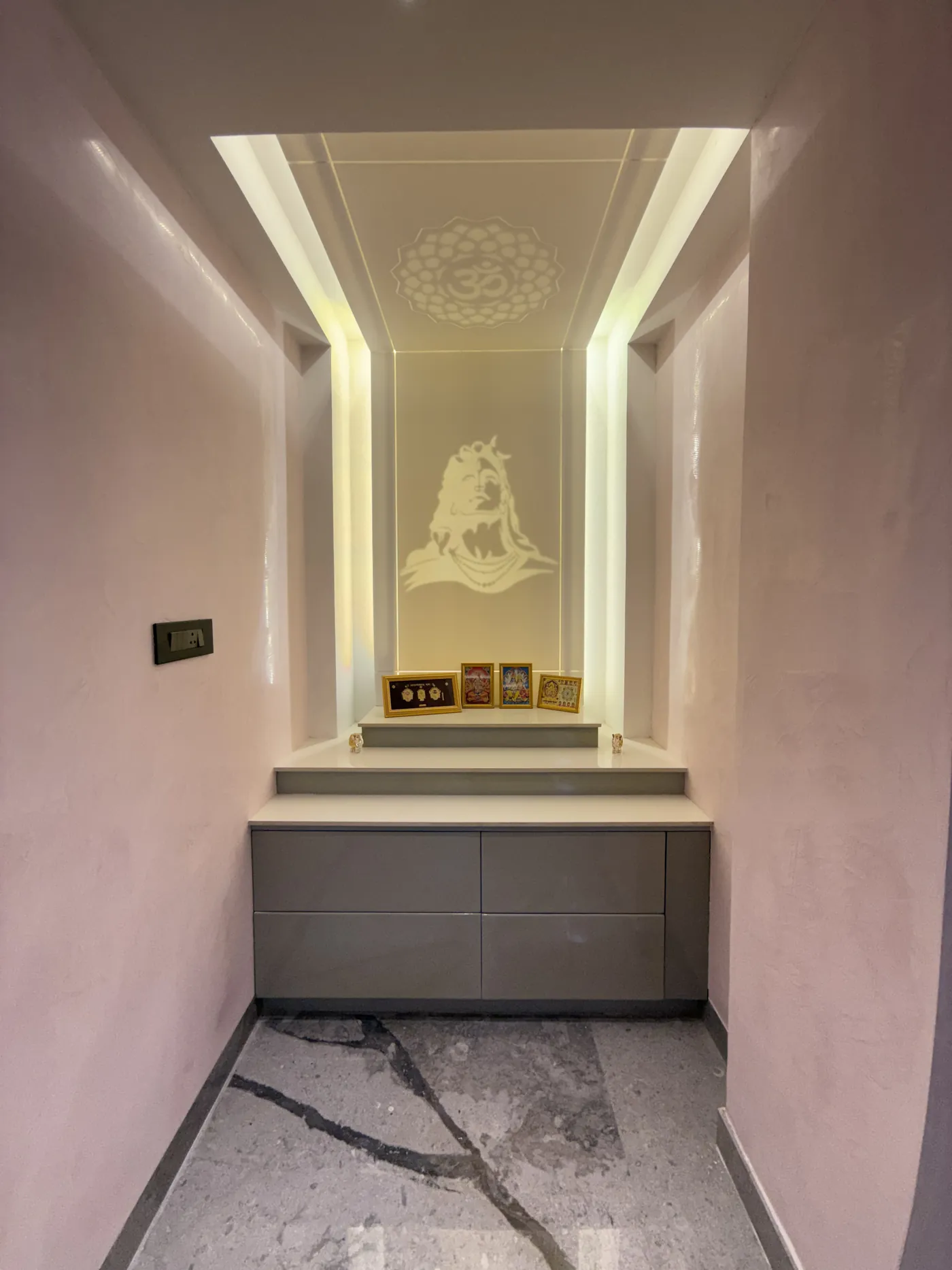 Puja niche with a carved backdrop and concealed warm lighting
