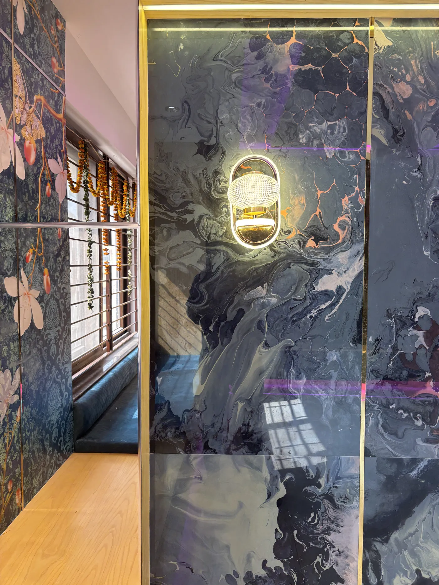 Floral marble-effect wall panel with a brass trim beside a mirror