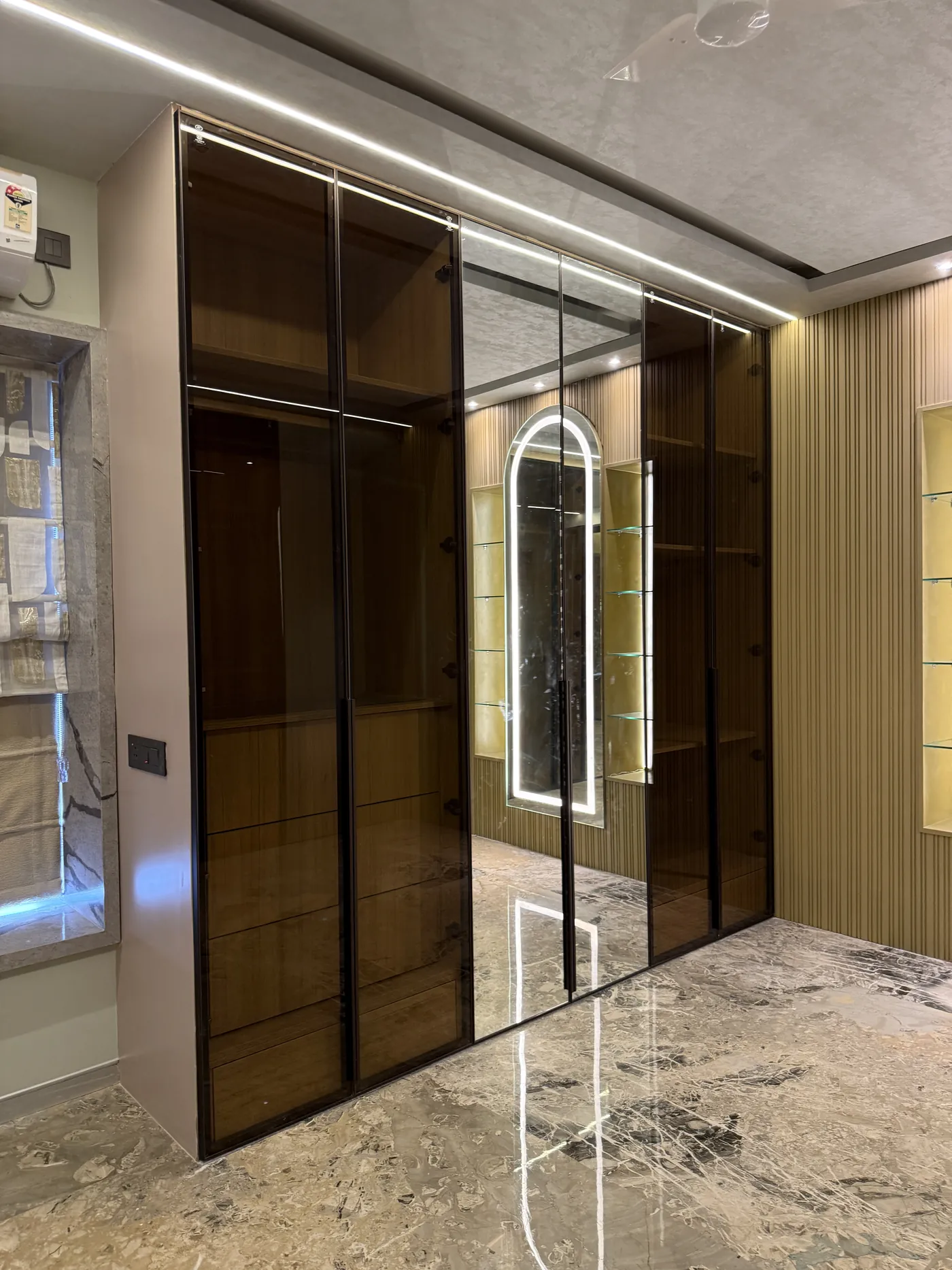 Sliding wardrobe with bronze mirrored panels along a corridor